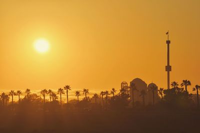 Silhouette palm trees against orange sky