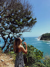 Woman standing by sea against sky