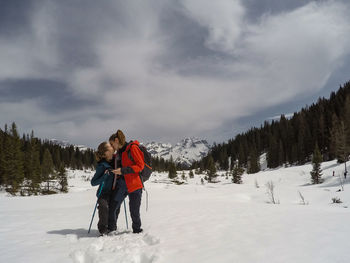 People standing on snow covered land against sky