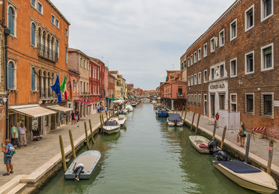 Canal amidst buildings in city against sky