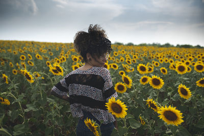 Woman standing amidst blooming sunflowers