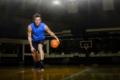 Man practicing basketball in court