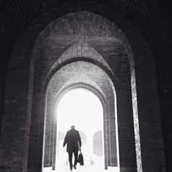 Rear view of woman standing in tunnel