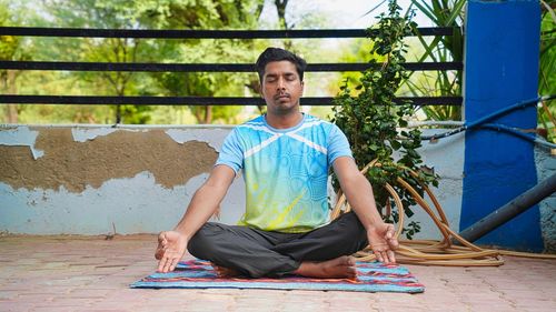 Handsome sporty indian young man exercising at home. yoga pose sitting. calm and happiness