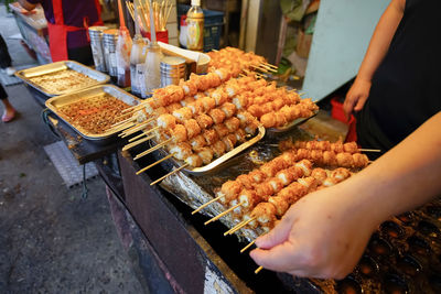 Cropped image of people on barbecue grill at market