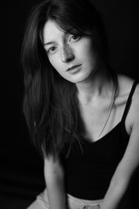 Portrait of young woman against black background