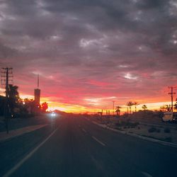 Scenic view of road against cloudy sky at sunset