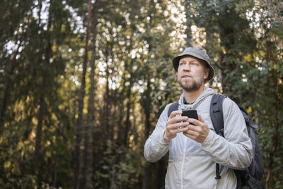 Young man using mobile phone in forest