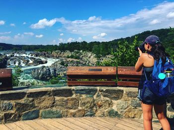 Rear view of woman photographing river from observation point