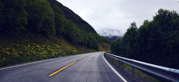 Road amidst trees against sky