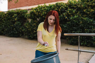 Midsection of woman putting paper in dustbin