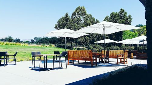 Empty chairs and tables against clear sky