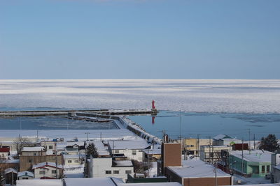 High angle view of buildings by sea against clear sky