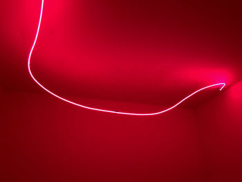 Close-up of illuminated lighting equipment against red wall