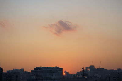 Silhouette city against orange sky