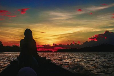 Woman sitting on beach at sunset