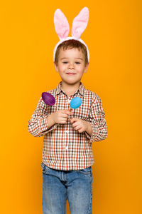 Portrait of boy standing against yellow background