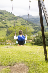 Rear view of boy swinging in playground