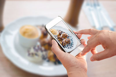Cropped image of hands photographing dessert in restaurant