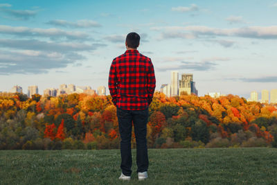 Rear view of man standing on field against sky