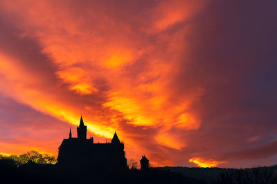 Silhouette buildings against dramatic sky during sunset