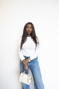 Portrait of young woman standing against white background