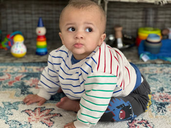 Portrait of cute baby boy playing with toy on floor