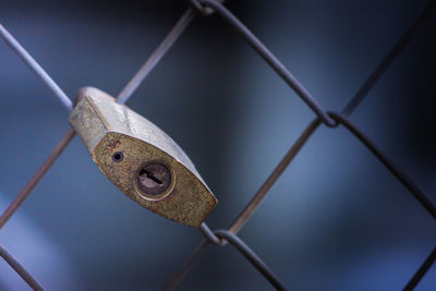 Close-up of padlock hanging on fence