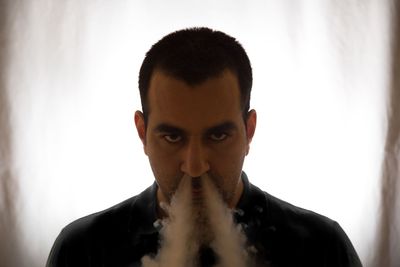 Close-up portrait of man exhaling smoke from nose