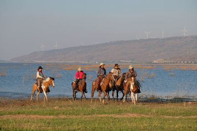 Group of people riding horses on field
