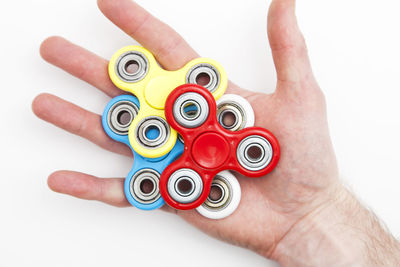 Close-up of hand holding toy blocks against white background