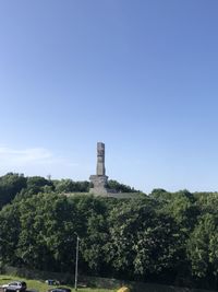 Built structure by trees against clear blue sky