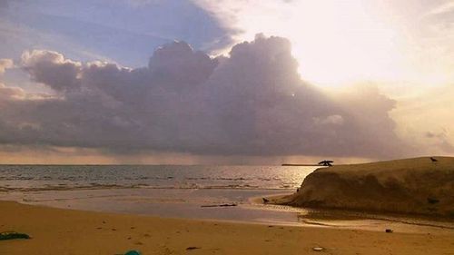 Scenic view of beach against cloudy sky