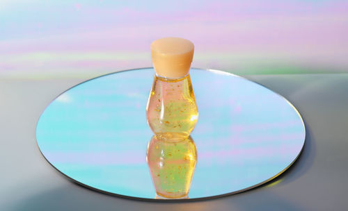 A bottle of cosmetic liquid with golden sparkles on a mirror. enzyme solution for face skin peeling