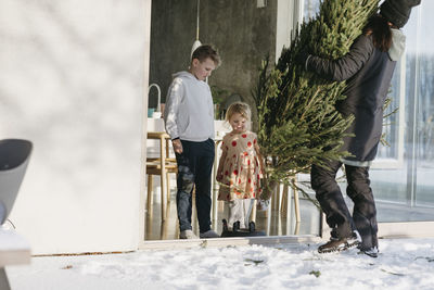 Woman carrying christmas in front of house