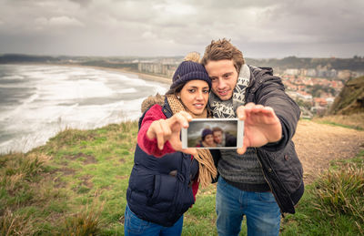 Full length of young man photographing on mobile phone