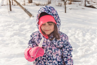 Smiling girl standing on snow during winter