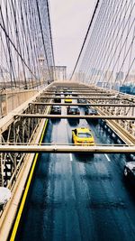 Suspension bridge in city against sky