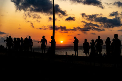 Silhouette people at beach against sky during sunset