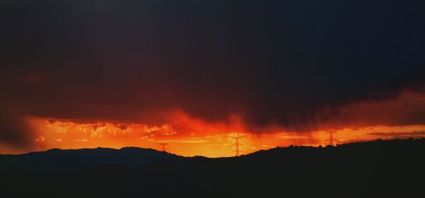 Scenic view of silhouette mountains against orange sky