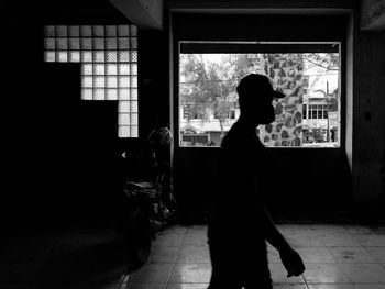 Silhouette man walking against window