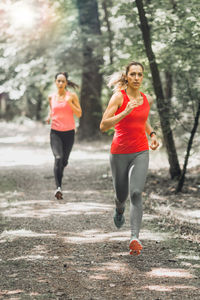 Full length of female athletes running in forest