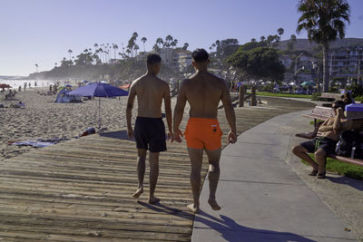 Rear view of men walking on sidewalk in city