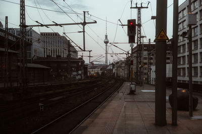 Railroad tracks by buildings in city against sky