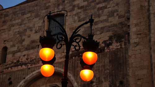 Low angle view of illuminated street light by castle at dusk