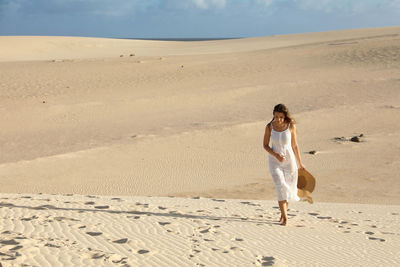 Full length of woman walking on sand at beach