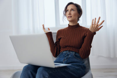 Portrait of young woman sitting on sofa at home