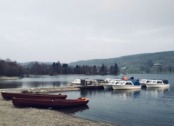 Boats moored in lake against sky