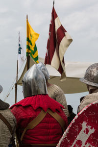 Rear view of men flag in water against sky