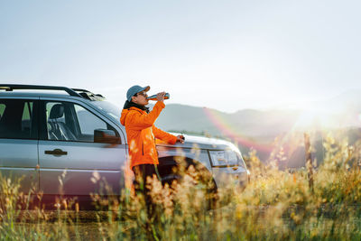 Rear view of woman standing on car